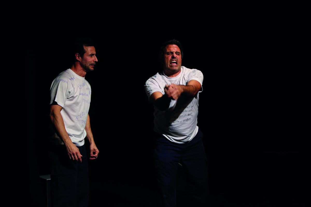 Dois atores da Página em Branco em cena, de t-shirt branca escrita