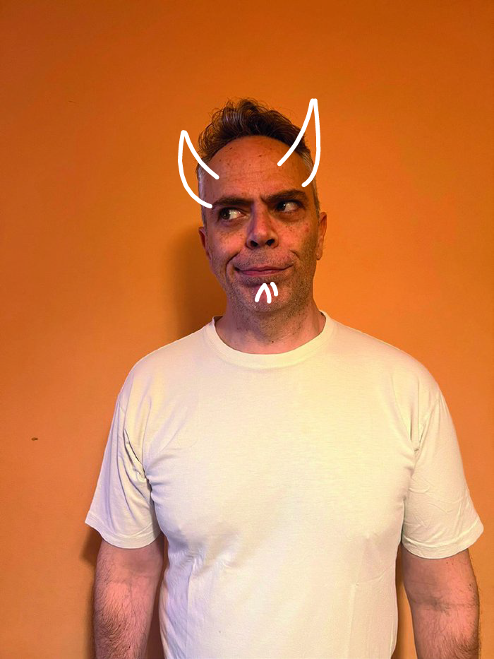 Retrato de Mário Bomba, de t-shirt branca e olhar de lado, sobre fundo cor de laranja